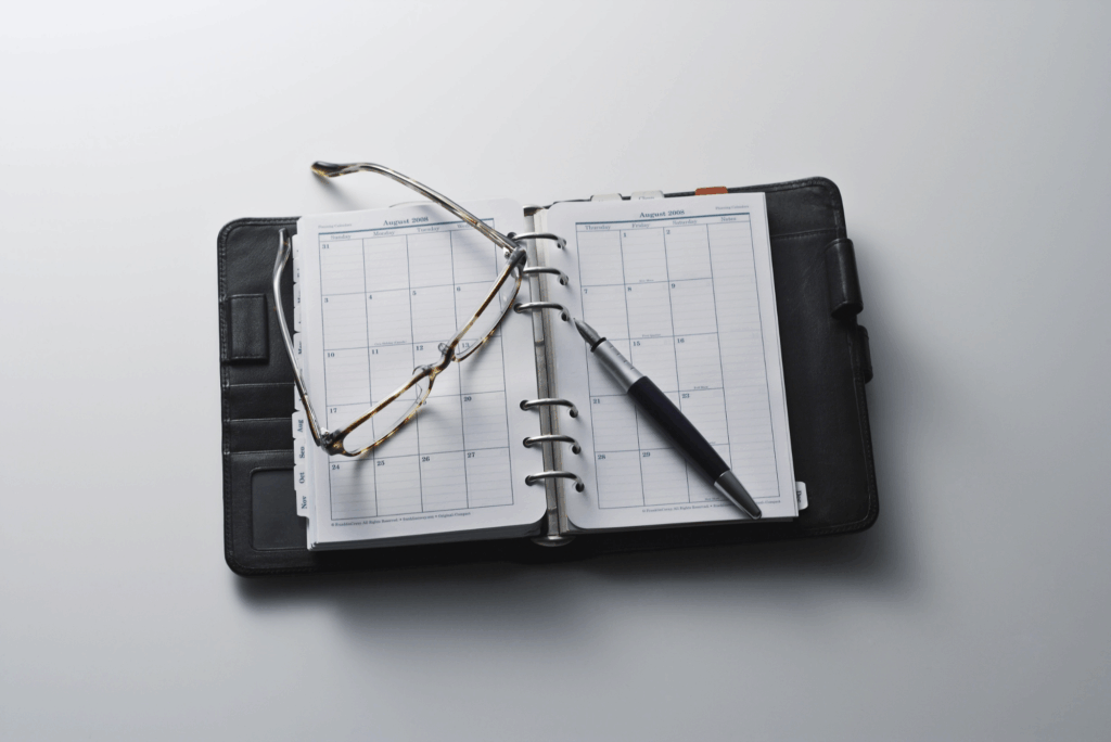 An open planner with a pen and glasses, representing careful planning and timing when hiring a Texas parole attorney.